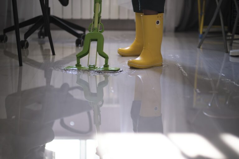 young boy in yellow rubber boots diligently cleaning up the aftermath of a flood in his apartment